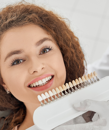 Patient smiling beside a porcelain veneer shade guide